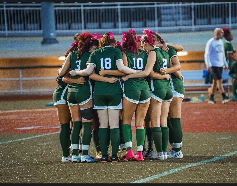 Central girls' team in a Pink Out game huddle, players wearing pink ribbons